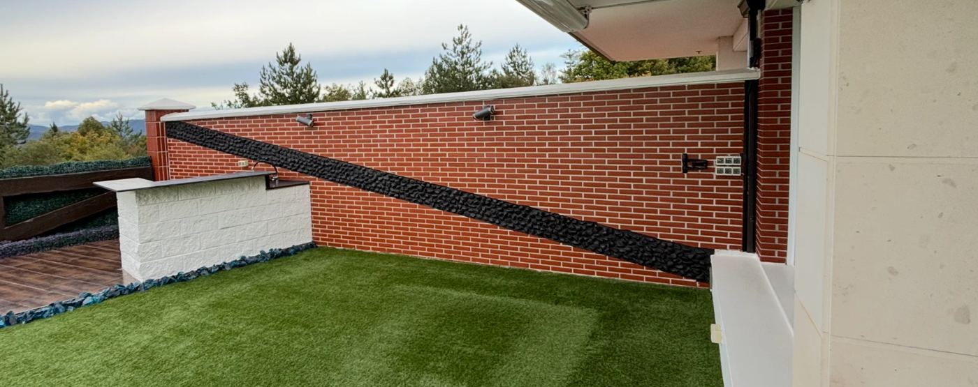 El mismo muro de terraza terminado en caravista con una franja de piedra